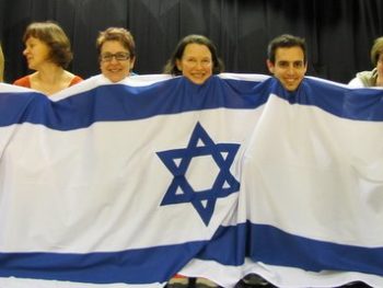 DVI Dancers in Finland, featuring Dr. Kristiina Ramo, Prof. Tapani Ramo, and Yuval Tabashi, choreographer and dance teacher from the Israeli Dance Institute in London. Look at the happy faces of the dancers standing behind the Israeli Flag.